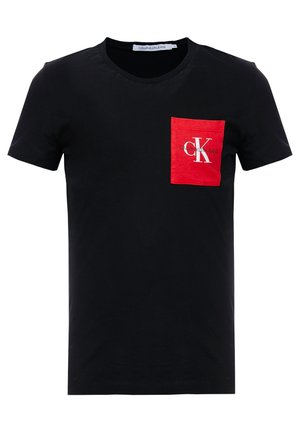 Musta puuvillane T-särk, ümar kaelus, millel on punane rinnatasku, kaunistatud valge Calvin Kleini logoga.