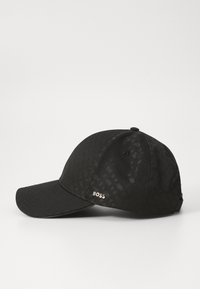Gorra negra con un sutil patrón texturizado, visera curva y detalle de marca. Hecha de una tela con un acabado suave y correa ajustable.