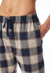 Pantaloni del pigiama in cotone a quadri con cintura elastica regolabile. La combinazione di colori include blu navy, beige e grigio con un motivo a quadri.