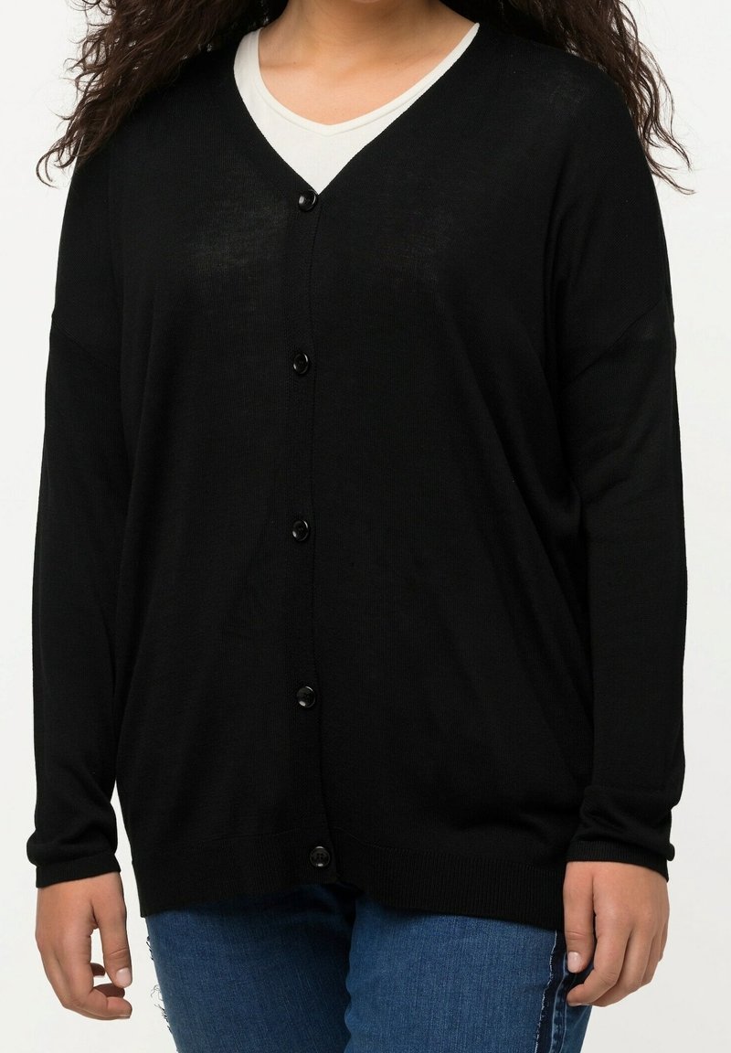 Schwarzer, langärmeliger Cardigan mit V-Ausschnitt, der große Knöpfe auf der Vorderseite hat, aus leichtem, strukturiertem Strickstoff gefertigt.