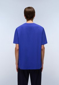 Short-sleeve, crew-neck t-shirt in vibrant blue cotton fabric. Relaxed fit with a straight hem, showcased from the back.