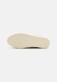 Scarpe Calvin Klein con suola in gomma testurizzata, di colore beige chiaro, caratterizzate da un branding discreto e una superficie di presa a motivo.
