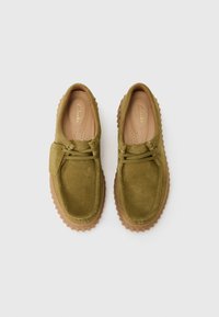 Chaussures en daim vert olive avec une semelle en caoutchouc, dotées d'un laçage, de détails cousus et d'une doublure intérieure rembourrée.