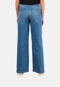 Jeans in denim blu a gamba larga con una finitura sbiadita, due tasche posteriori e un logo ricamato su subtile sulla tasca destra.