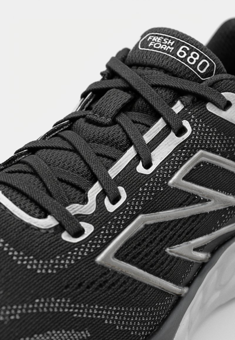 Zapatilla de correr negra con parte superior de malla texturizada, acentos reflectantes y etiqueta Fresh Foam 680. Cuenta con cordones y una suela acolchada.