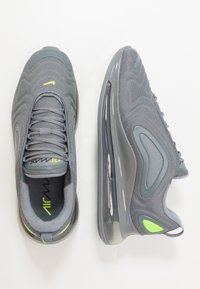 Szare buty sportowe z siateczkowym wierzchem, gumową podeszwą i poduszką powietrzną. Posiadają neonowo-żółte akcenty i zaokrąglony design noska.