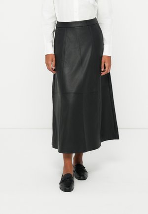 Zwarte leren maxirok met een gladde textuur, voorzien van paneelstiksels en een taillering, gecombineerd met zwarte platte schoenen.