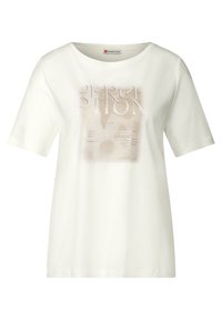 T-shirt en coton blanc à manches courtes, présentant un imprimé graphique sur le devant dans des tons beiges doux, incluant du texte et des formes abstraites.