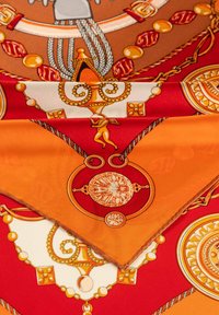 Seidenstoff mit aufwendigen barocken Mustern in Rot, Orange und Gold, einschließlich Ketten, Medaillons und einer kleinen Engel-Figur.