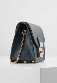 Grå läderhandväska med en strukturerad design, guldfärgade detaljer och en texturerad yta. Har en kedjerem och ett lockstängning.