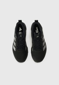 Czarne buty sportowe z teksturowaną cholewką z siateczki, trzema odblaskowymi paskami oraz wyściełanym językiem. Posiadają podeszwę z bieżnikiem zapewniającą przyczepność.