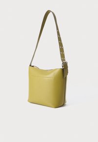 Gulld leather skulderveske med myk tekstur, med et flatt design og en stropp med sølvnagler. Glidelås på toppen og frontlomme.