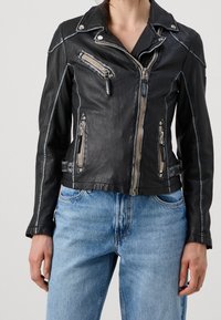 Black leather biker jacket with silver zippers, snap buttons, and contrasting stitching. Features multiple zippered pockets and a fitted design.