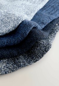 Knitted fabric layers in varying shades of blue, featuring a textured weave with distinct color transitions and a soft finish.