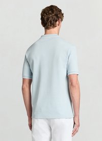 Hellblaues Polohemd aus strukturiertem Stoff mit kurzen Ärmeln, das einen dünnen weißen Besatz am Kragen und an den Ärmelsäumen aufweist.