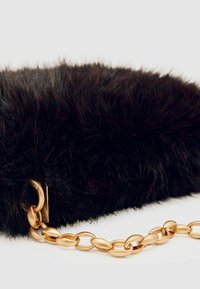 Svart faux fur clutchväska med en guldkedjestropp med ovala länkar. Texturen är mjuk och plyschig, vilket framhäver dess lyxiga utseende.