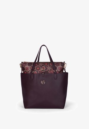 Tmavě fialová kožená taška přes rameno s dvojitými uchy, obsahující červenou a černou vzorovanou zipovou kabelku uvnitř a zlaté kruhové logo.