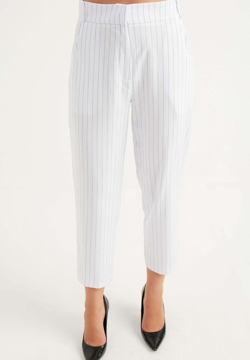 Witte pinstripe broeken met een rechte snit, voorzien van zijzakken en een middelhoge tailleband, gecombineerd met zwarte puntige hakken.