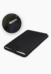 Copertura di quaderno nera con un esterno liscio e una texture sottile. Presenta una chiusura sicura a strap e uno slot per uno smartphone o dispositivo.