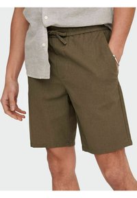 Olivgrüne Shorts aus leichtem Material mit einem Kordelzugbund, Seitentaschen und bequemem Schnitt. Glatte Textur mit minimalem Nähen.