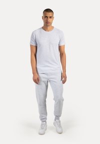 Jasnoszary t-shirt z krótkim rękawem i okrągłym dekoltem, zestawiony z dopasowanymi jasnoszarymi dresami. Strój charakteryzuje się luźnym krojem i miękką fakturą.
