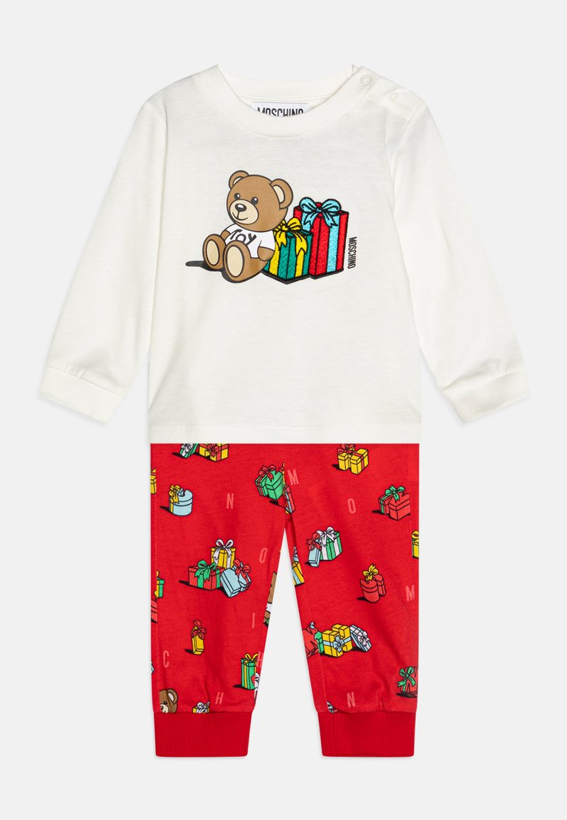 Valge pika varrukaga särk, millel on karu graafika ja kinkekotid, sobitatud punaste pükstega, millel on värvilised kinketrükised. Puuvillane materjal, vabaja lõige.