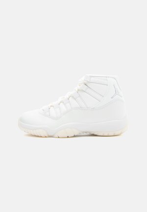 Białe sneakersy wysokie, z gładkiej skóry, o smukłym designie, gumowej podeszwie i trzema wyraźnymi oczkami na sznurówki. Logo Jumpman po stronie.