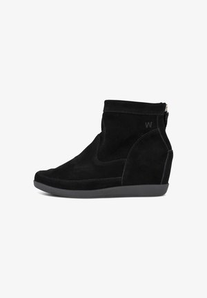 Stivali ankle in suede nero con suola a zeppa, dotati di una zip laterale e design strutturato. Texture liscia con dettagli di cucitura sottili.
