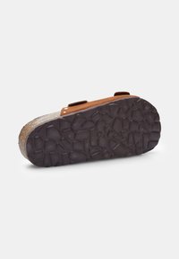 Brown suede sandal with a cork footbed, featuring a patterned rubber outsole for grip and two adjustable straps on the top.