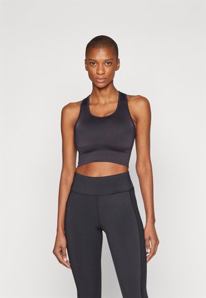 Zwarte sportbeha met een ronde hals en brede schouderbanden, gecombineerd met zwarte highwaisted legging met contrasterende stiksels. Glad materiaal.