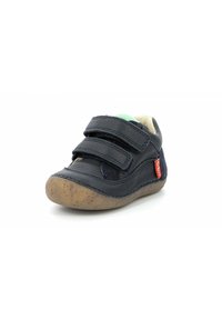 Zapato de cuero azul oscuro con dos correas de Velcro, punta redondeada, suela de goma texturizada en marrón claro y pequeña etiqueta de marca roja en el lateral.