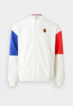 White zip-up jacket with blue and red color-blocked sleeves. Features a Nike logo patch and a stand-up collar. Smooth fabric texture.