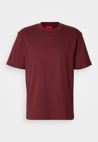 T-shirt uni rouge foncé à manches courtes avec col rond et petit logo "HUGO" centré près de l'encolure.