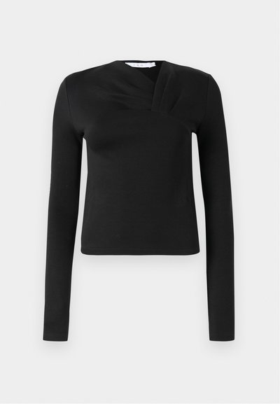 Mustaline musta pikad varrukad tops, millel on sissepoole keeratud disain, valmistatud siledast kangast. Omab lühikest pikkust ja V-kujulist kaelust. Ilma mustrite ja aktsentideta.