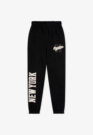 Czarne spodnie dresowe z elastycznym pasem. Na bokach widnieją nadruki "BROOKLYN" i "NEW YORK" w kremowym, pogrubionym foncie.