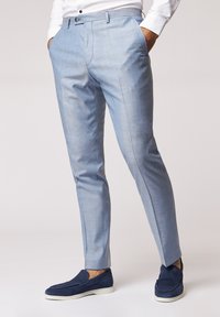 Hellblaue maßgeschneiderte Hosen mit strukturiertem Finish, ausgestattet mit Vordertaschen und schmaler Passform. Kombiniert mit navy blauen Slippern.