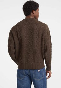 Brauner Kabelstrickpullover mit Rautenmuster und geripptem Saum. Hat eine lässige Passform und überschnittene Schultern, von hinten betrachtet.
