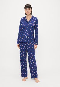 Conjunto de pijama azul marinho com padrões florais, apresentando uma blusa com botões e calças soltas, feito de tecido suave para conforto.