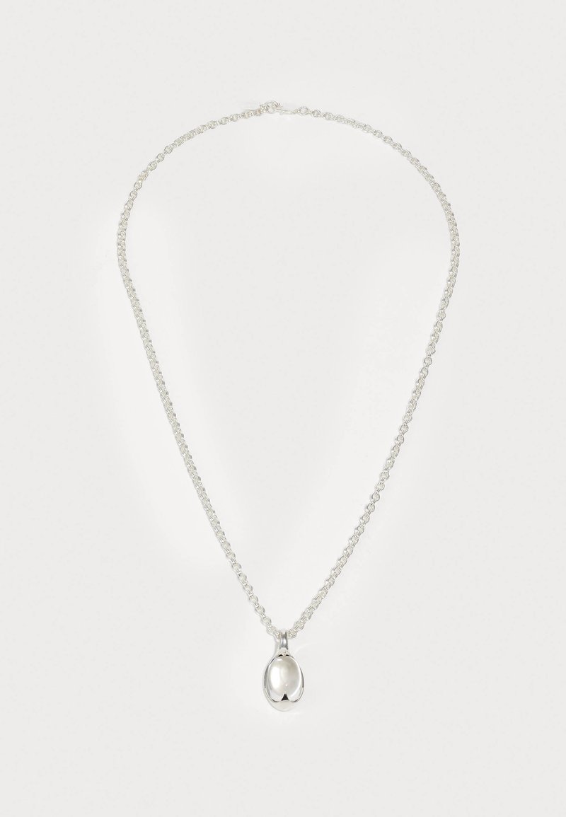 Ασημένιο κολιέ με λεπτή αλυσίδα και οβάλ μενταγιόν. Το μενταγιόν έχει λείο, ανακλαστικό επιφάνεια και είναι συνδεδεμένο με έναν απλό βρόχο.