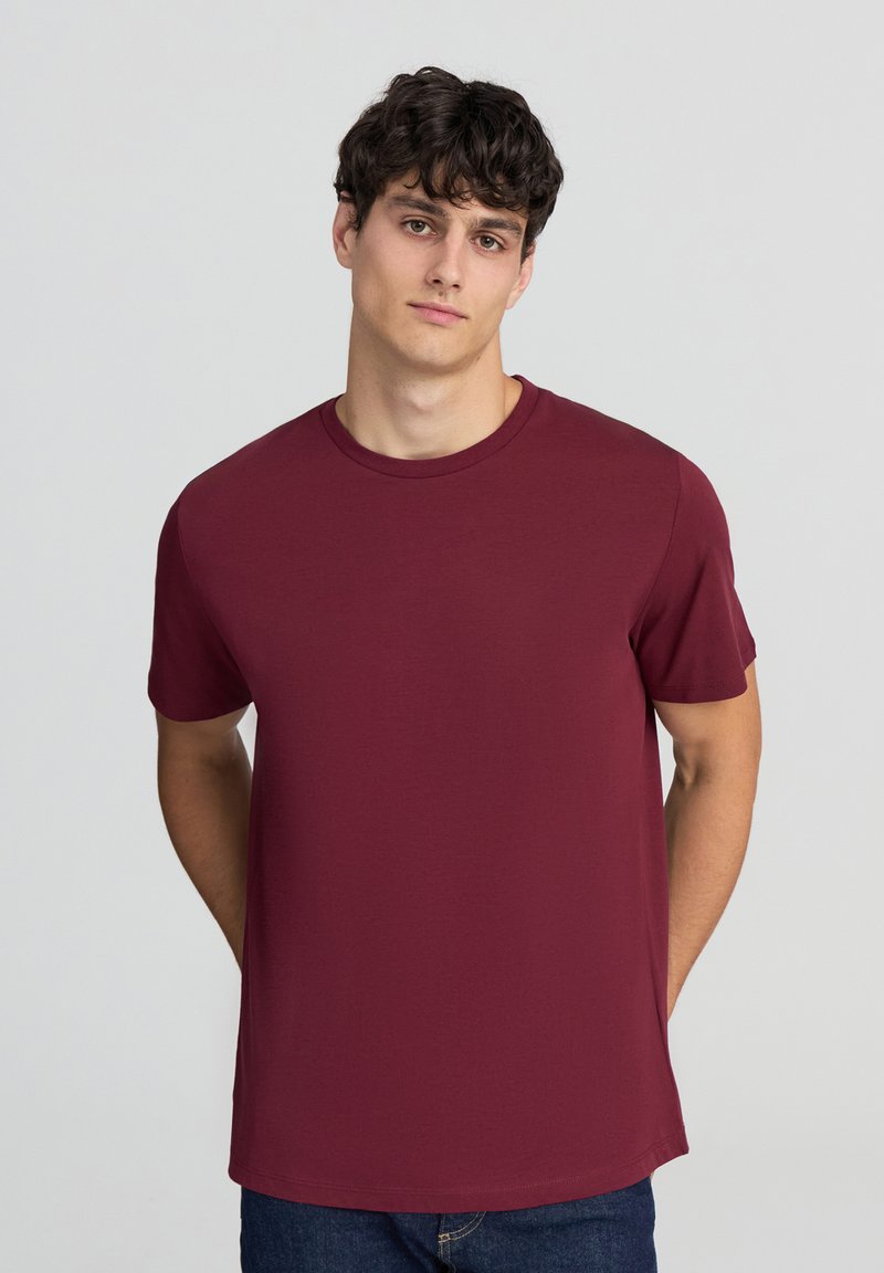 T-shirt in cotone bordeaux con collo rotondo, maniche corte e vestibilità rilassata, caratterizzato da una texture liscia e senza loghi o motivi visibili.