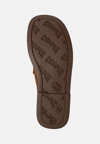 Brown rubber sole with textured "CAMPer" logo pattern, stitched edges, and rounded heel. Flat design, suitable for casual footwear.