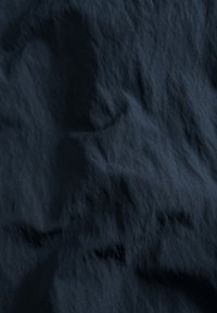 Marineblå tekstureret stof med en krøllet overflade, der har bløde bølger og subtile variationer i lys og skygge.