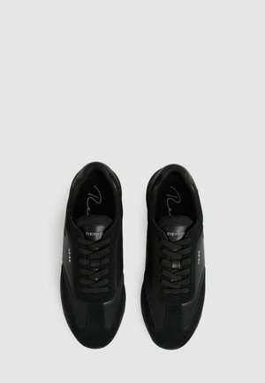 Sorte sneakers med en kombination af ruskind og mesh-materialer, prydet med snørebåndsdesign, glatte konturer og diskrete logo-detaljer på siderne.