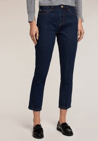 Tmavě modré denimové džíny se středním střihem, zkrácenou délkou do kotníků, jemnými detaily na přední části a zlatými kovovými doplňky na předních kapsách.