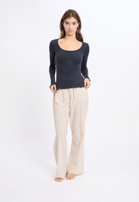 Granatowa, prążkowana bluzka z długim rękawem i kwadratowym dekoltem, zestawiona z kremowymi spodniami z szerokimi nogawkami w delikatne pionowe paski.