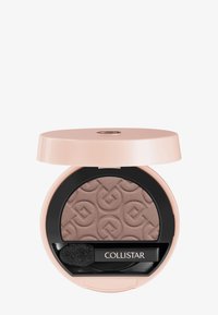 Ombre à paupières en poudre compacte dans un emballage rose pâle, avec un produit de couleur brun clair texturé et une éponge applicatrice noire.