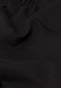 Schwarzer Baumwollstoff mit glatter, dehnbarer Textur und subtiler glänzender Oberfläche, ausgestattet mit einem elastischen Bund und flachen Nähten.