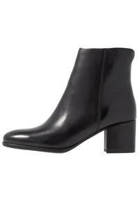 Bota de cuero negro de tobillo con punta afilada, textura suave y tacón de bloque. Costuras a lo largo de los laterales.