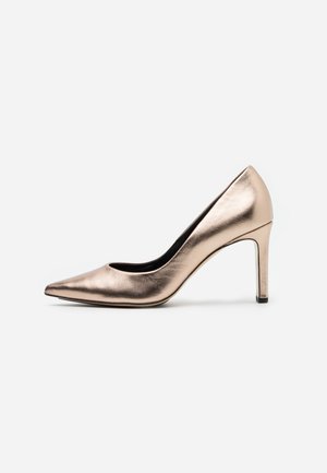Zapato de tacón alto de color oro rosa metálico con punta afilada, textura de piel suave y una silueta elegante. Interior negro con un tacón delgado.