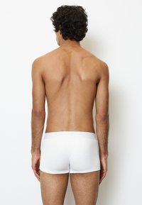 Weiße Baumwoll-Boxershorts mit glatter Textur und elastischem Bund, von hinten betrachtet, hervorgehoben durch die Passform und das schlichte Design.